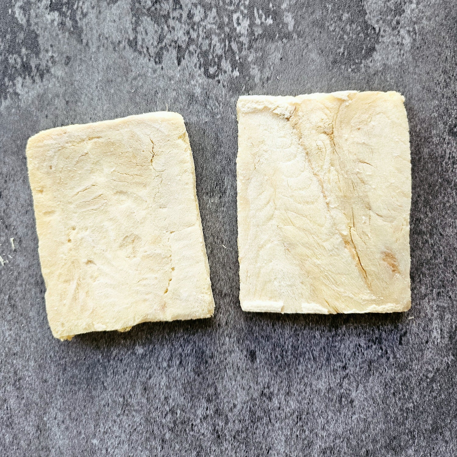 Two square pieces of Pollock fillets on a gray surface