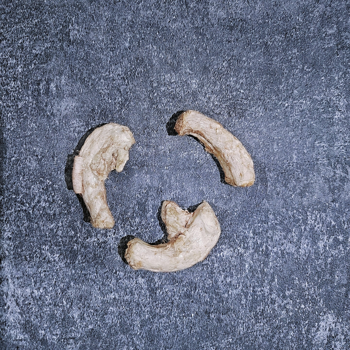 Three pieces of dried quail necks on a textured gray surface