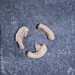 Three pieces of dried quail necks on a textured gray surface